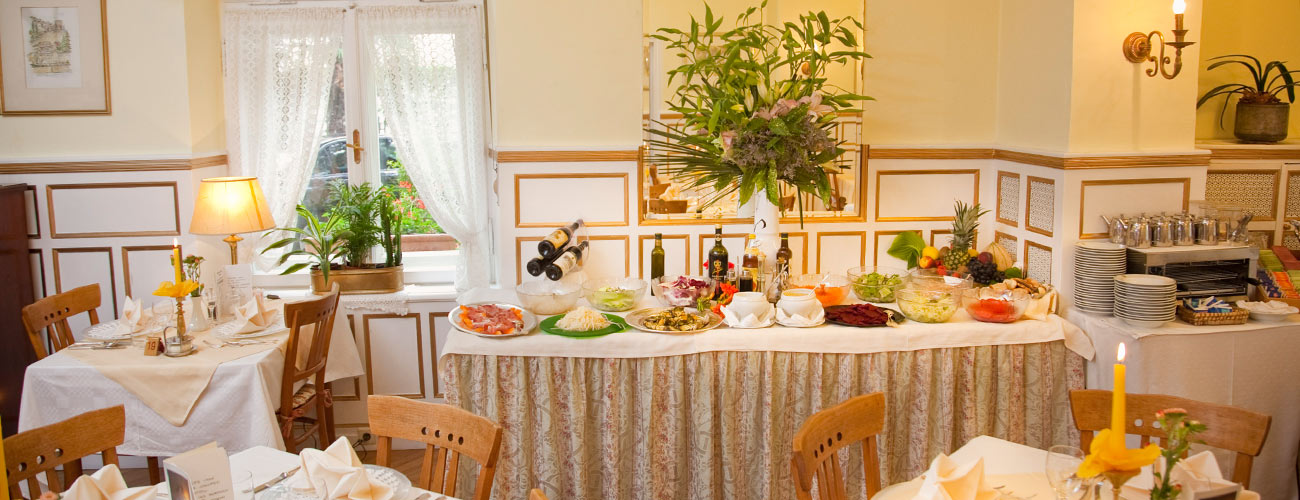 Ansicht auf das Salatbuffet und ein paar gedeckte Tische im Speisesaal im Hotel Westend