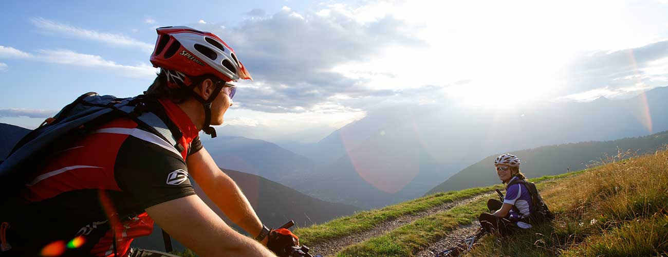 Zwei Radfahrer bei einem Bikeausflug auf einer grünen Wiese bei Sonnenuntergang