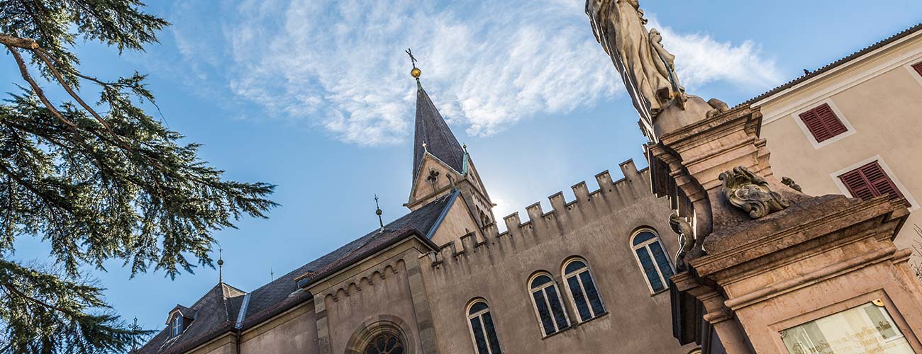 Piazza con statua e chiesa a Merano in Alto Adige