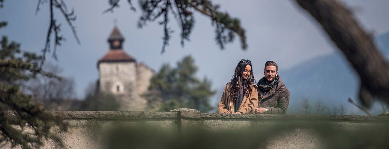 A couple on a bridge overlooking the city of Merano