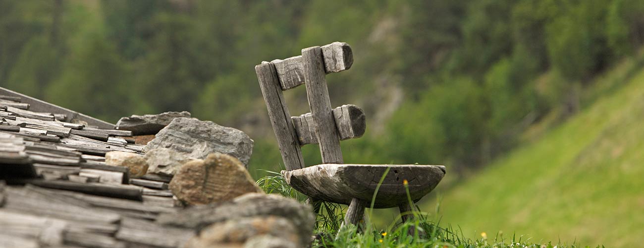 Detailaufnahme einer Holzbank mit Holzbrettern vor einer grünen Naturlandschaft